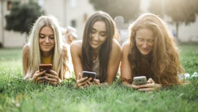 Female friends browsing smartphone on lawn